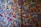 A vibrant display of colorful circular stickers densely packed on a wall, each with various symbols and text. The stickers are of multiple colors, including blue, yellow, red, green, and pink, creating a mosaic-like appearance.