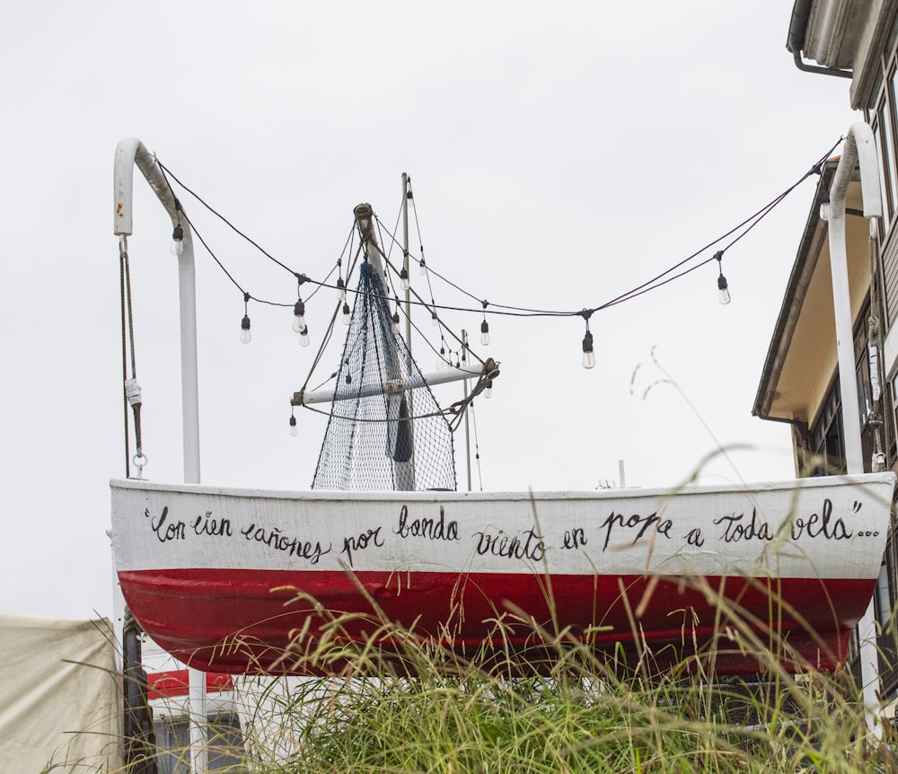 Un barco rojo y blanco sentado al lado de un edificio alto