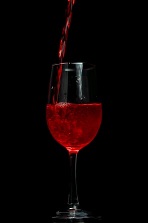 a glass of red wine being poured into it
