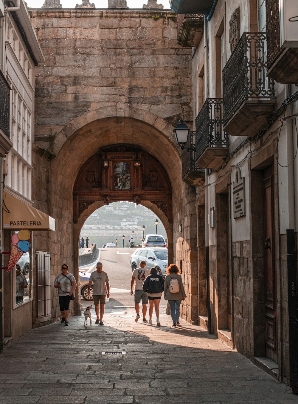 a group of people walking down a street under an archway