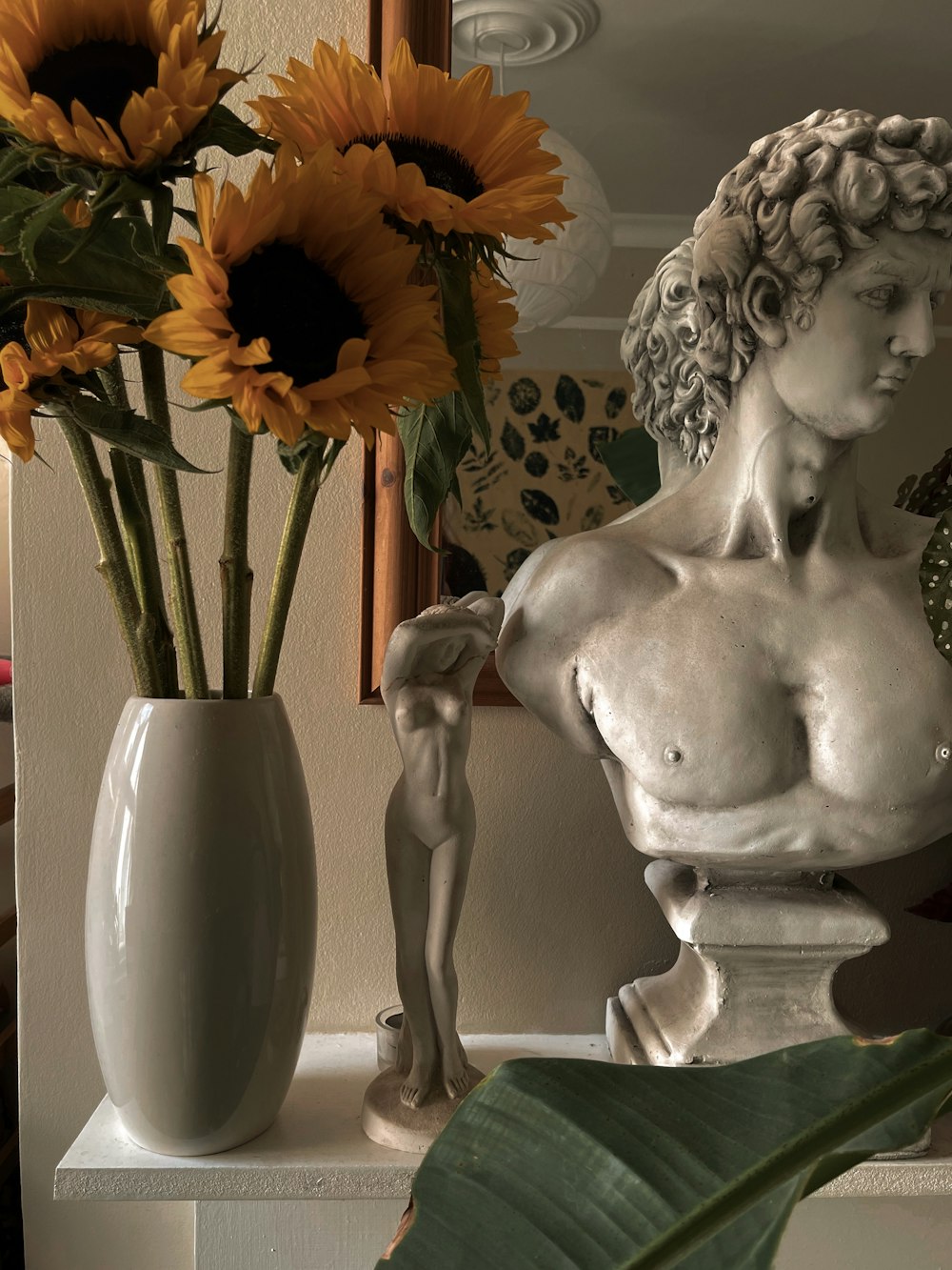 a vase with sunflowers and a statue of a woman