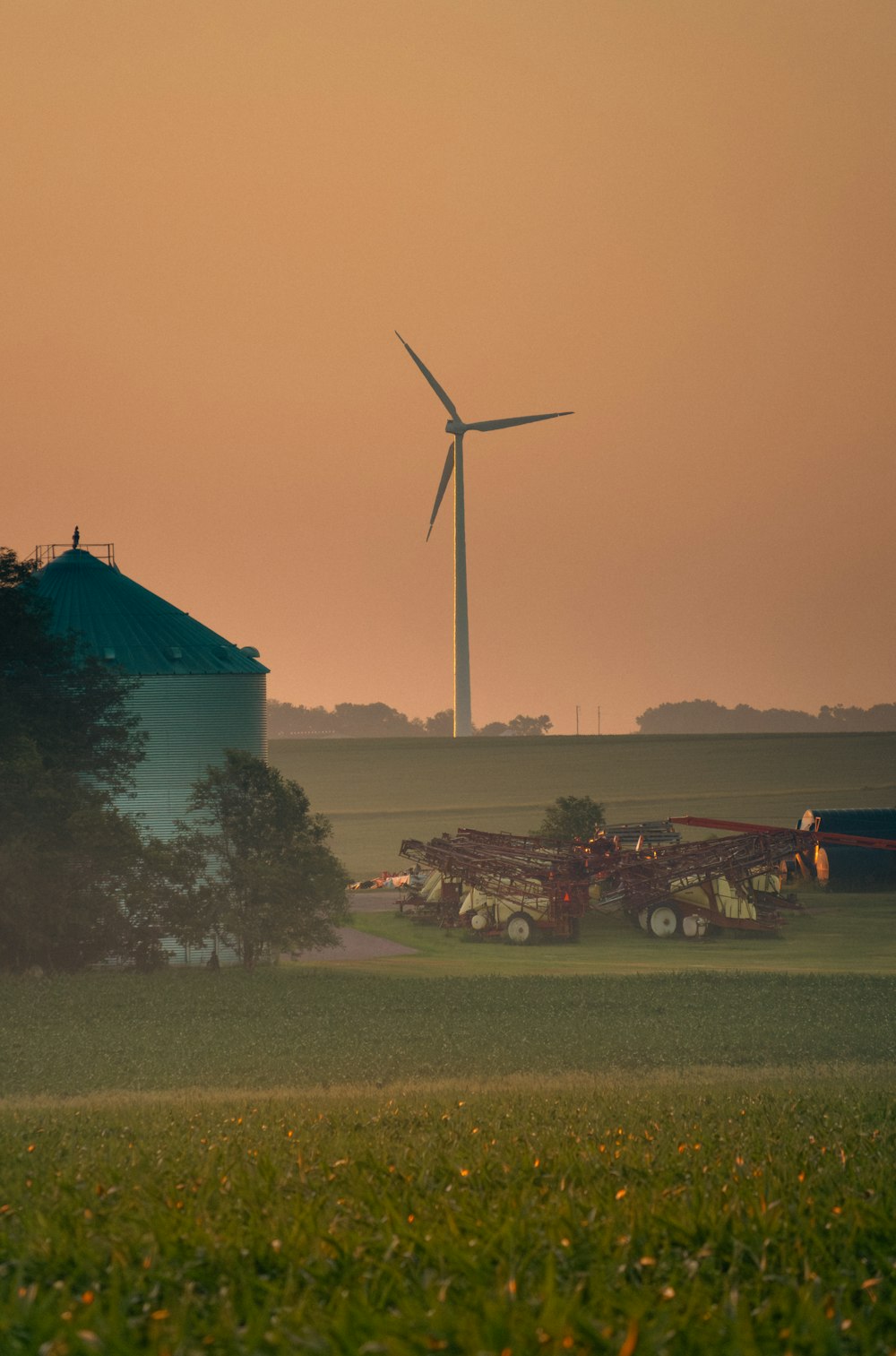 a farm field with a wind turbine in the background