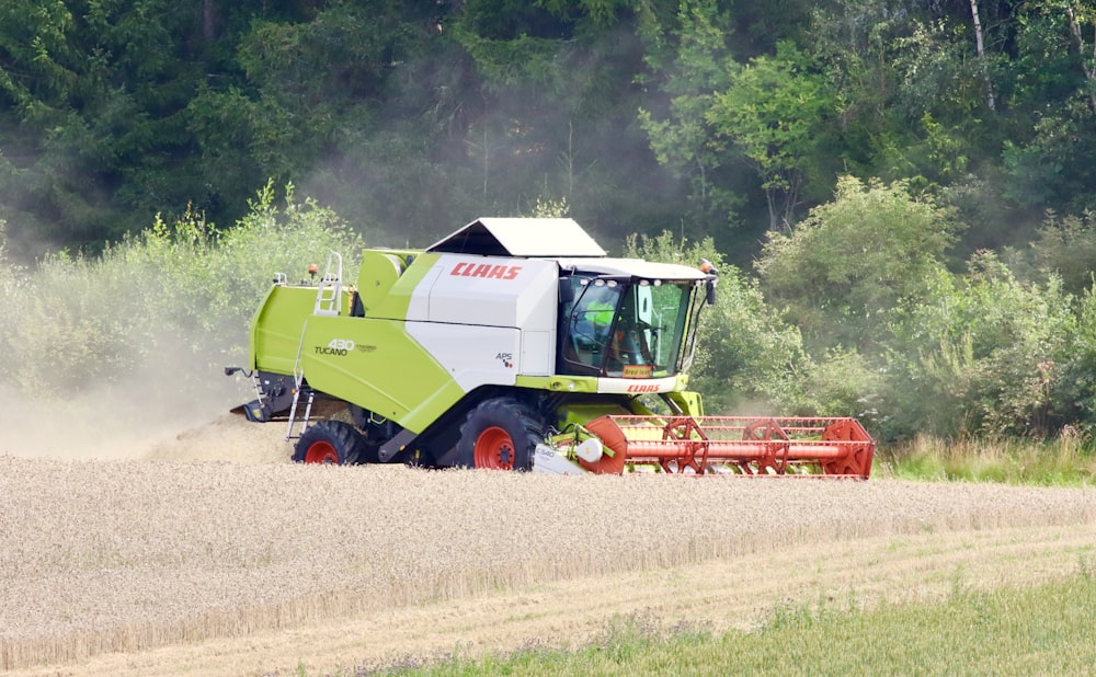 Una cosechadora verde y blanca está conduciendo a través de un campo