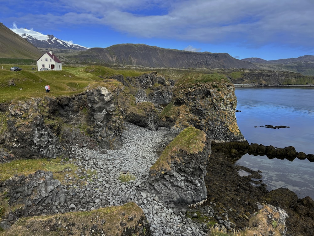 a house on a rocky shore with mountains in the background