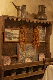 A rustic wooden shelf adorned with small potted plants and framed art pieces.