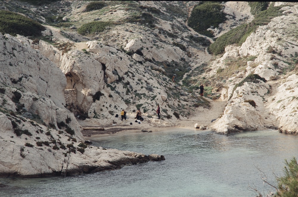 a group of people standing on a rocky cliff next to a river