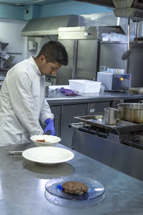 Chef preparing gourmet dishes using a combined oven in a professional kitchen.