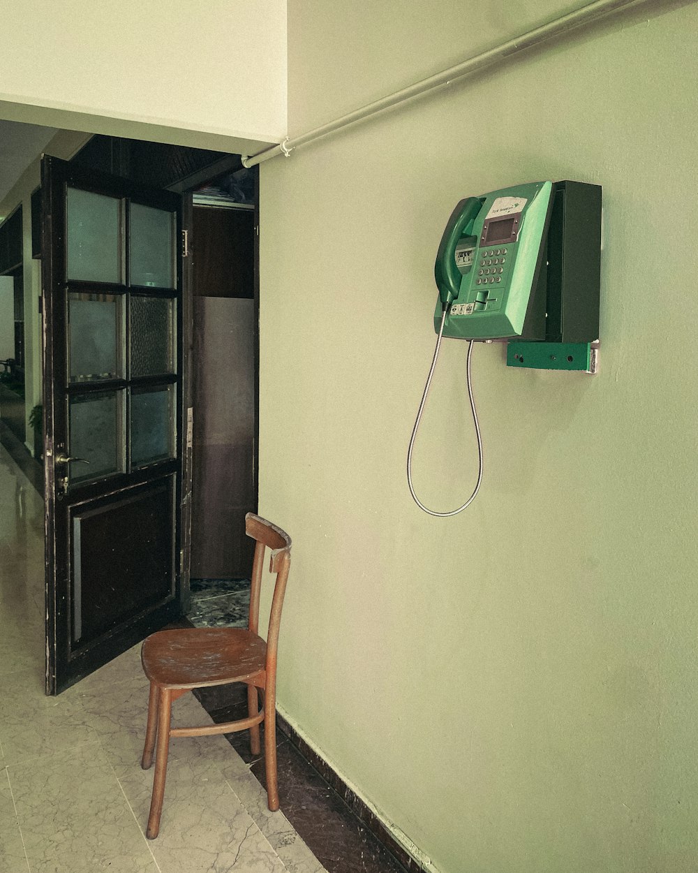 a chair sitting in front of a phone on a wall
