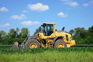 A friendly excavator operator waving from a John Deere mini excavator on a sunny farm lot.