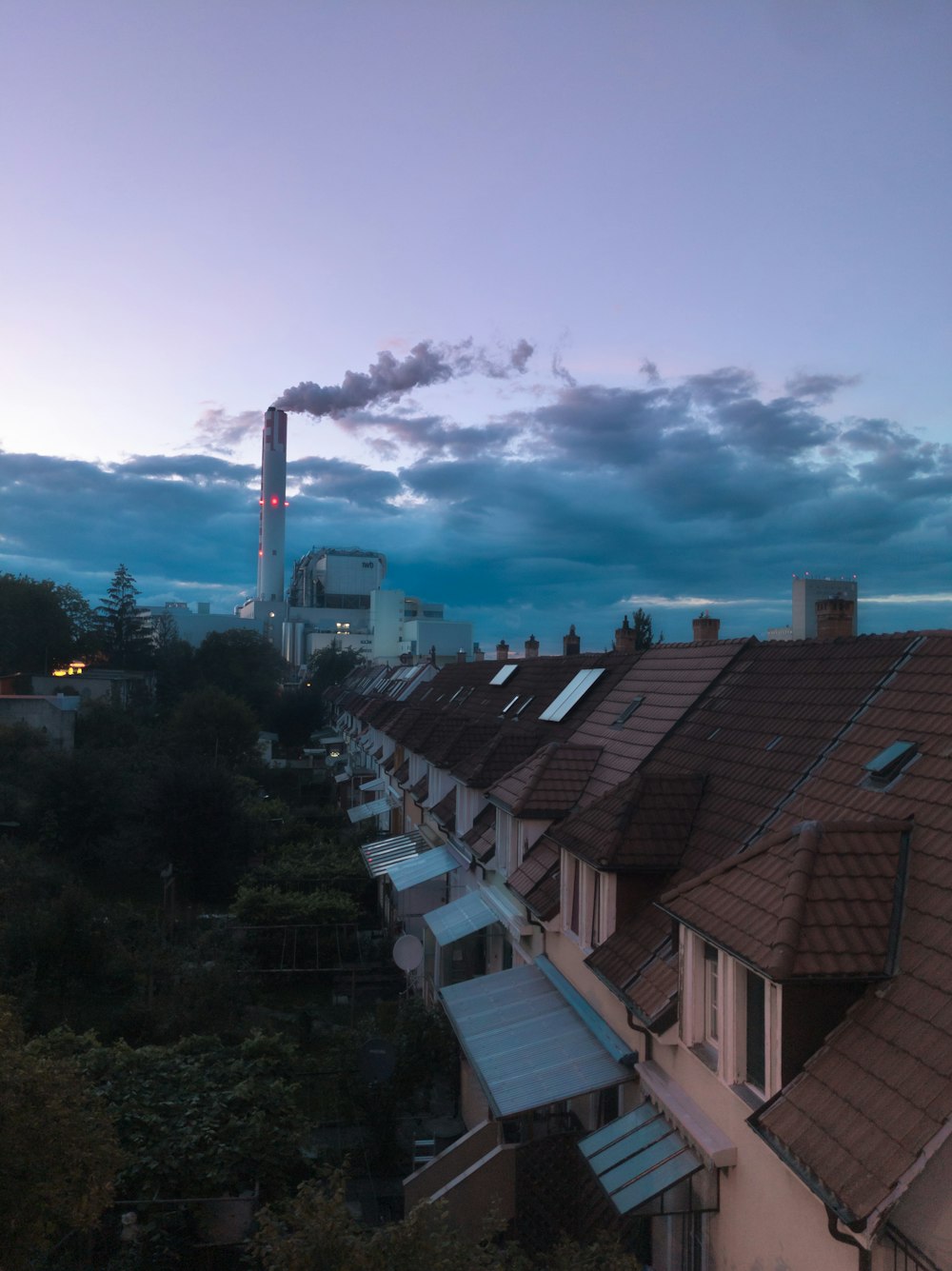 a row of houses with a smoke stack in the background