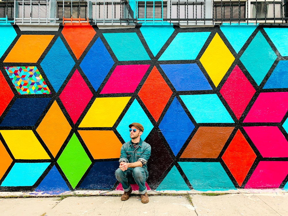 a man sitting in front of a colorful wall