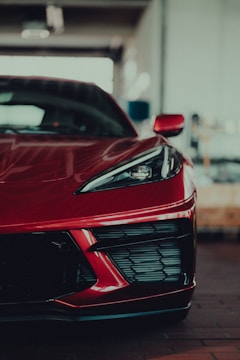 A close-up shot of a sleek, custom muscle car with a shiny red paint job under bright garage lights.