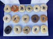 A display case filled with a variety of bagels, cream cheeses, and toppings.