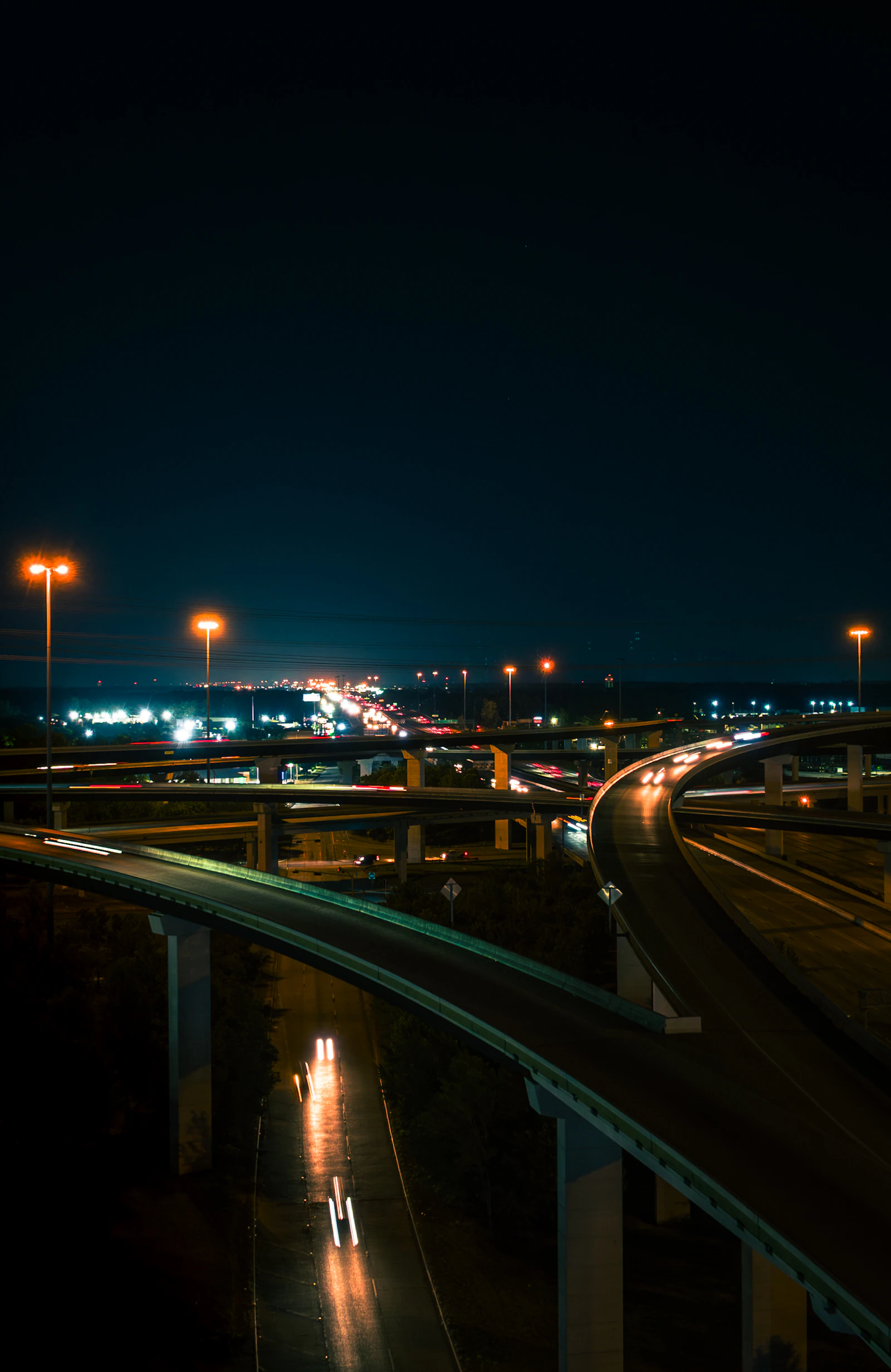 Night view of a highway interchange with sodium lamps and traffic light streaks