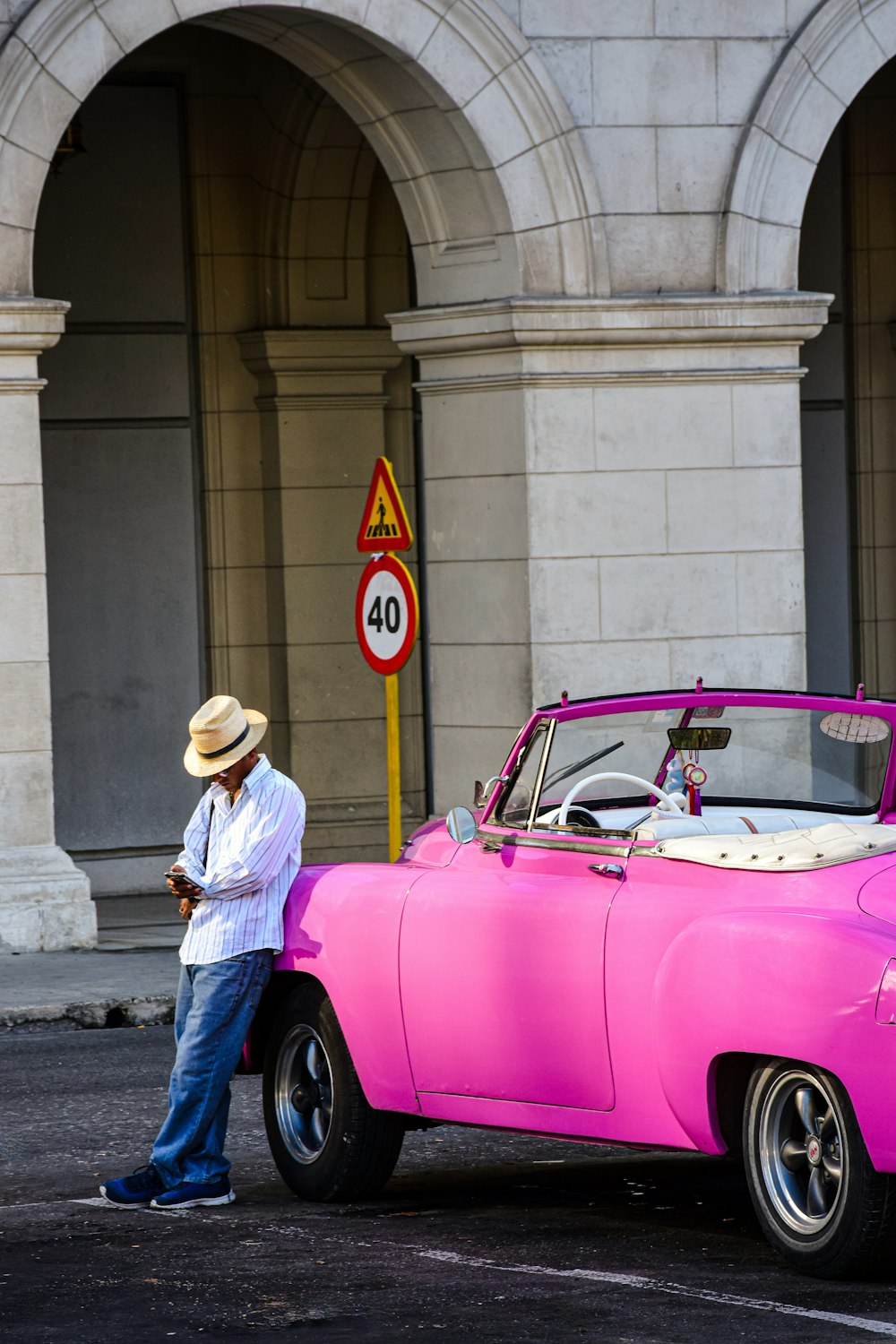 a man standing next to a pink car