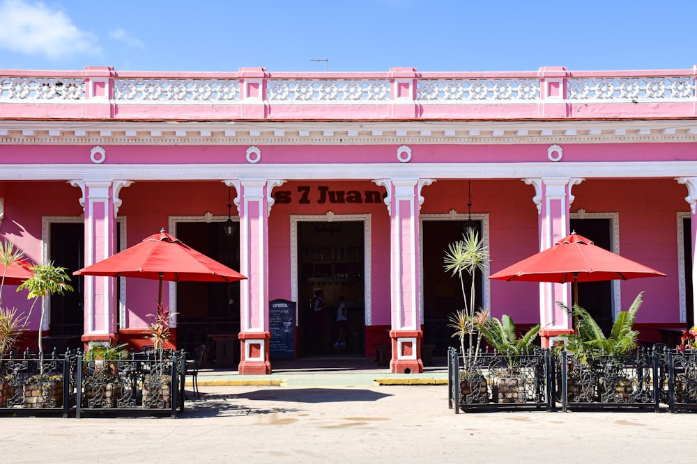 a pink building with red umbrellas in front of it