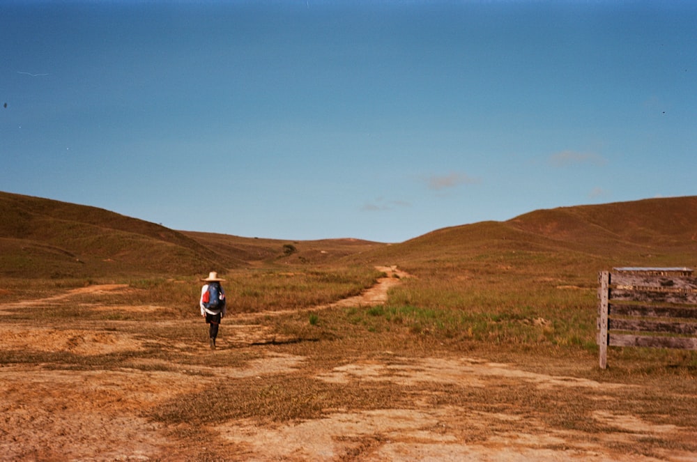 a person in a hat walking on a dirt road