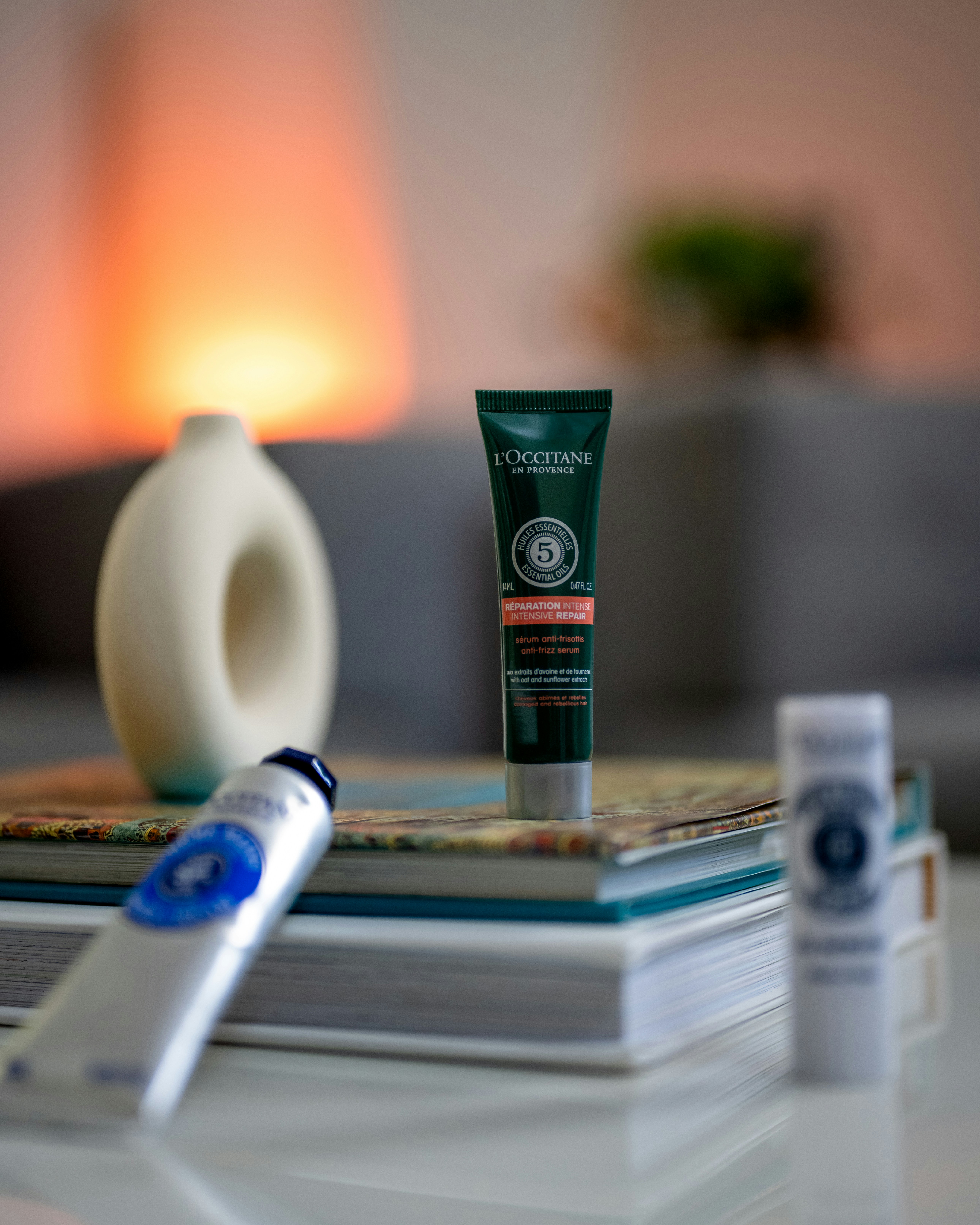 a white vase sitting on top of a table next to a tube of L'Occitane product