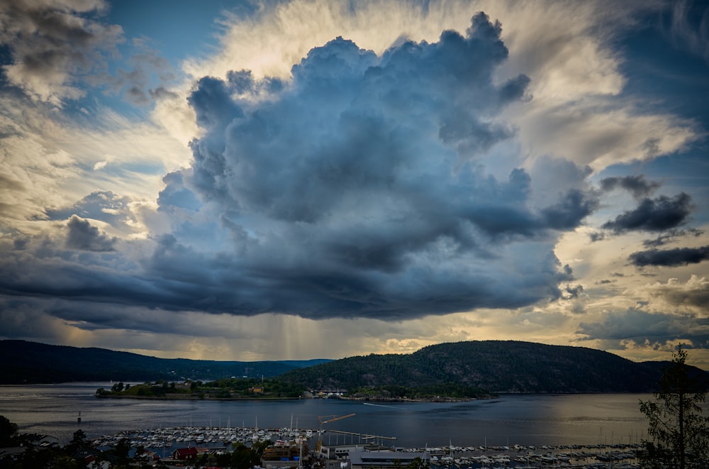 a cloudy sky over a harbor with boats in the water