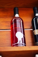 A bottle of red or rosé wine displayed on a wooden shelf. The label reads 'Tourónio Douro' and features a minimalist design with a silhouette of a person bending over. The bottle is next to another wine bottle that is partially visible.