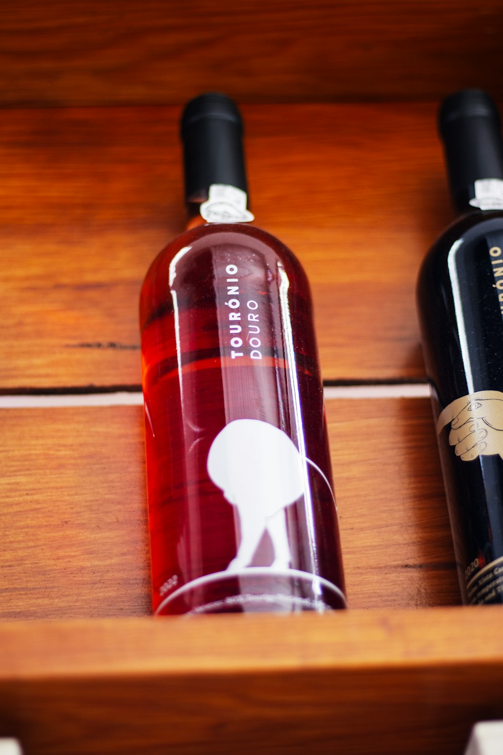 three bottles of wine sitting on a wooden shelf