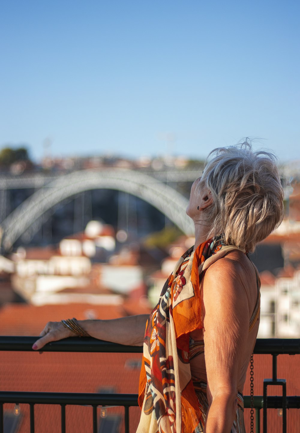 a woman standing on a balcony with a view of a bridge