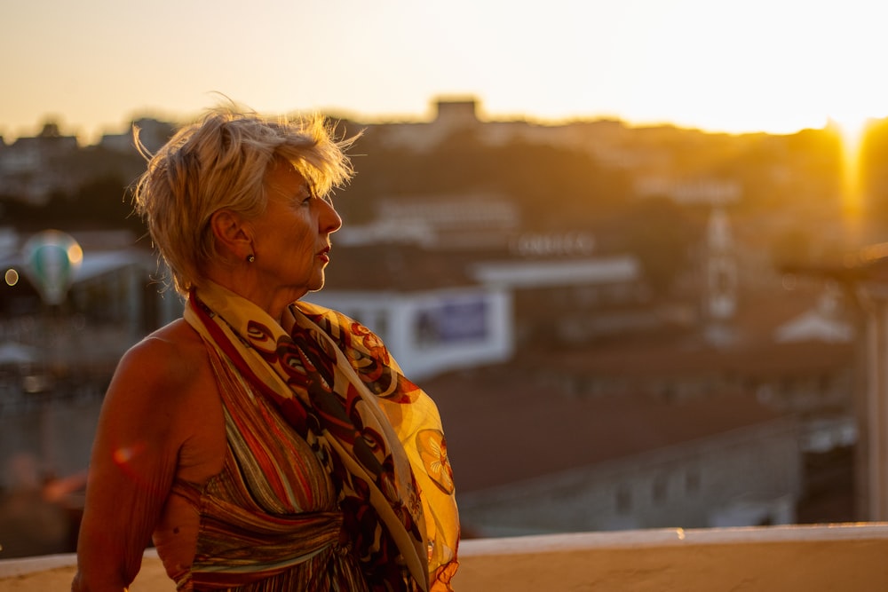 a woman wearing a scarf standing on top of a roof