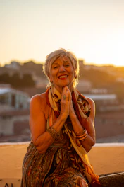 a woman sitting on a ledge with her hands clasped