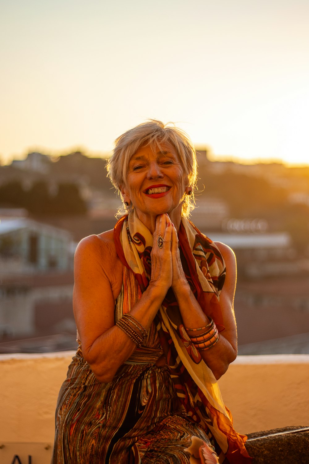 a woman sitting on a ledge with her hands clasped