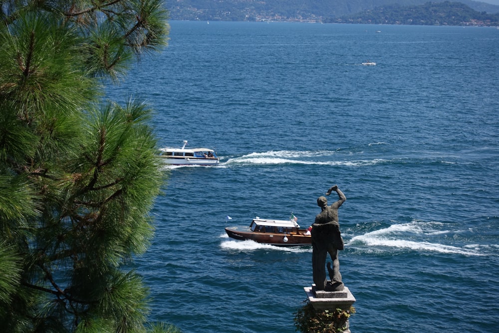 a statue of a man standing on top of a rock next to a boat