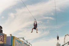 a man hanging from a rope above a carnival