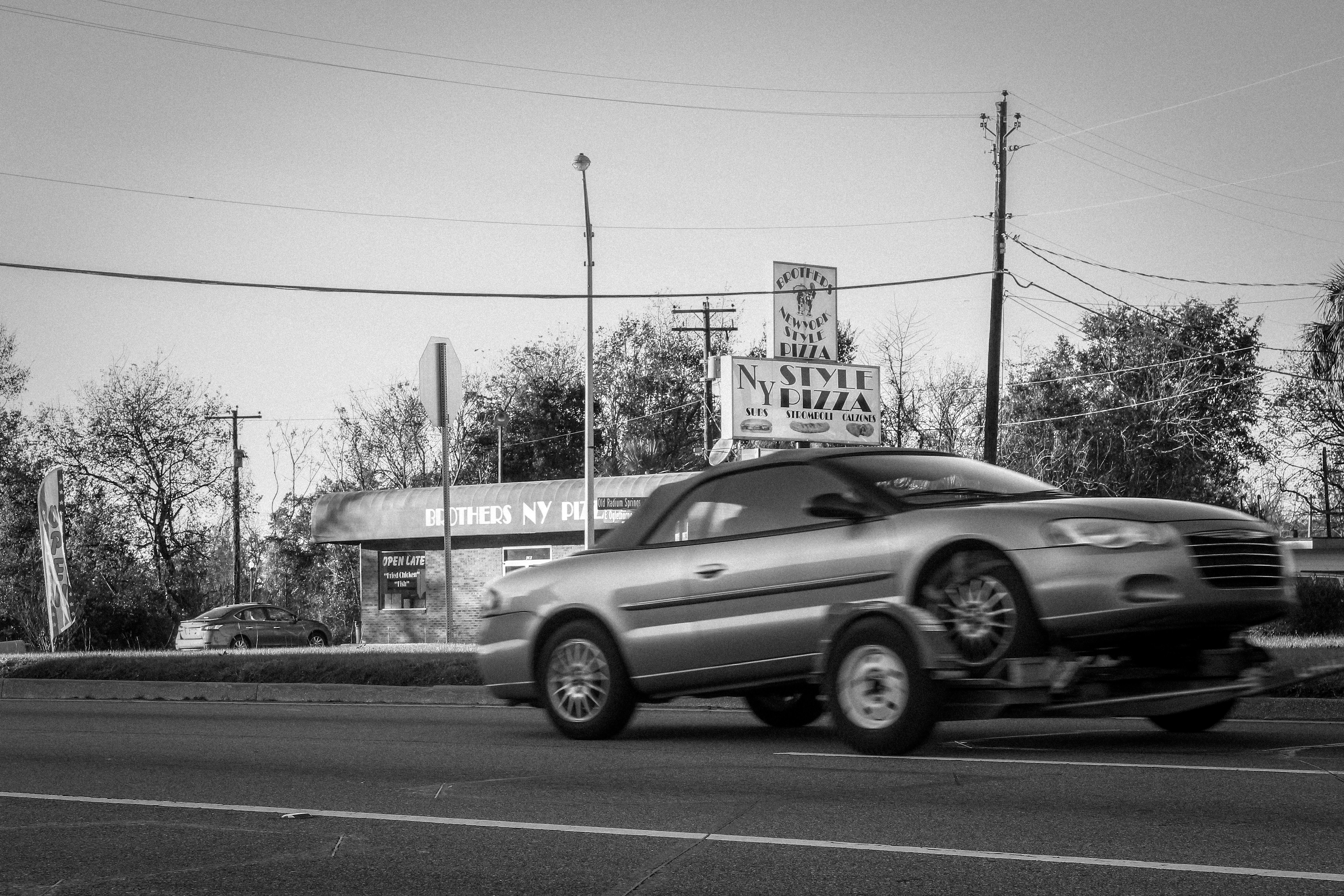 a silver car driving down a street next to a building