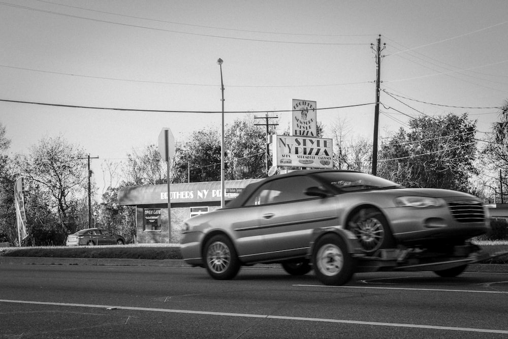 a silver car driving down a street next to a building