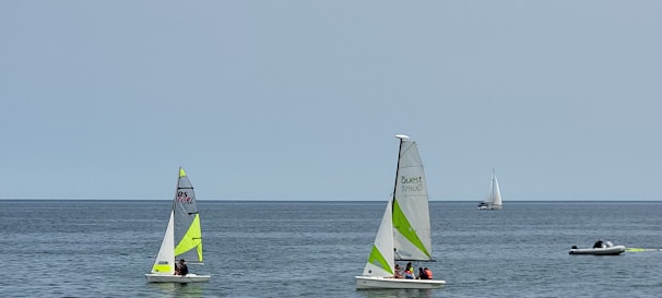 Group of children sailing small boats on a calm lake, smiling and focused.