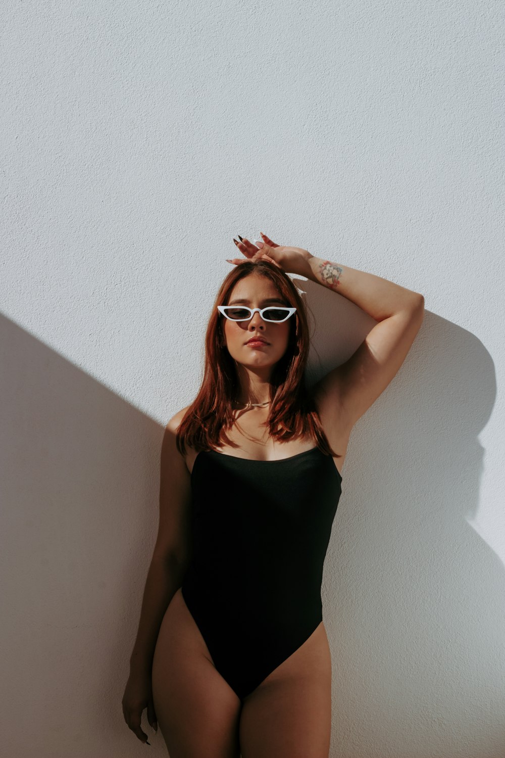 a woman in a black bodysuit and sunglasses