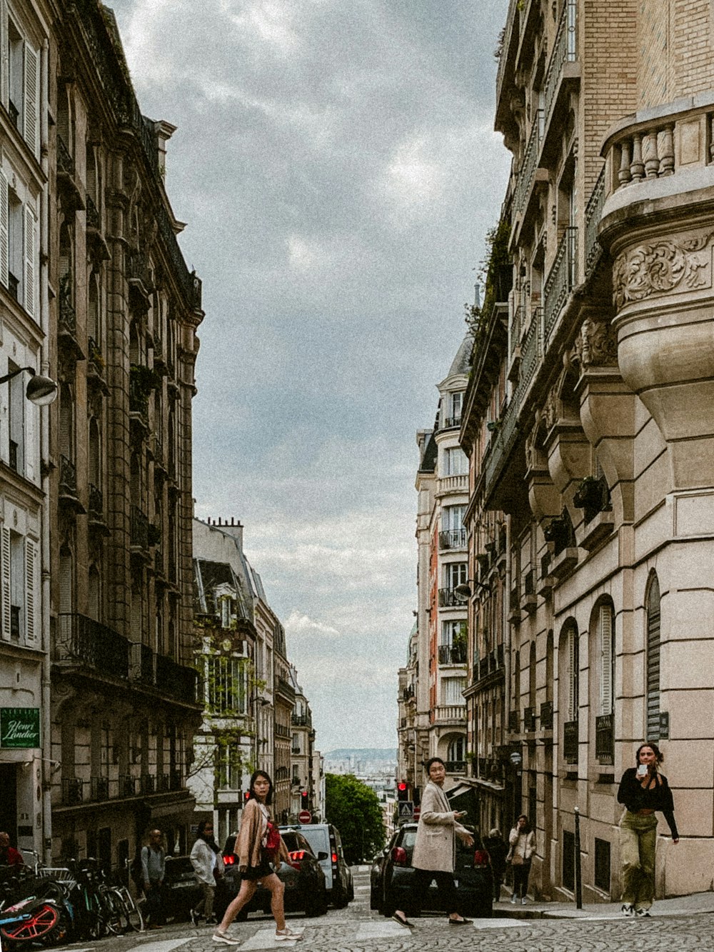 a couple of people walking down a street next to tall buildings