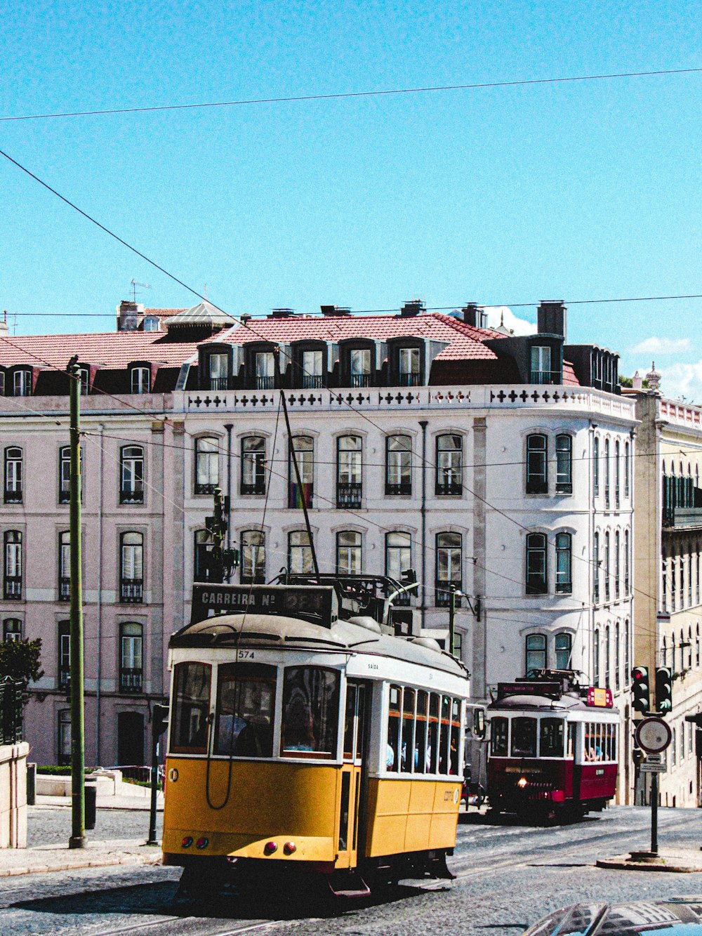 a yellow trolley driving down a street next to tall buildings