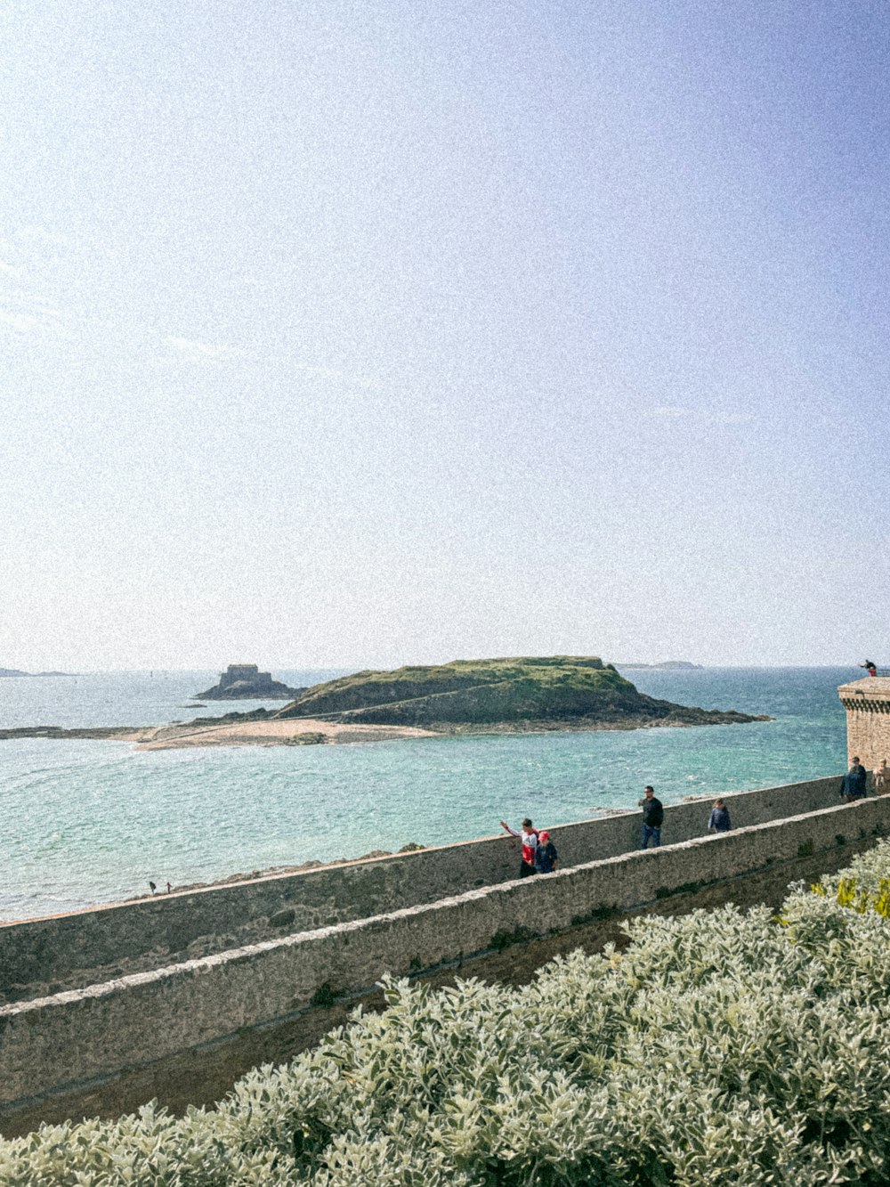 a group of people standing on the side of a road next to the ocean