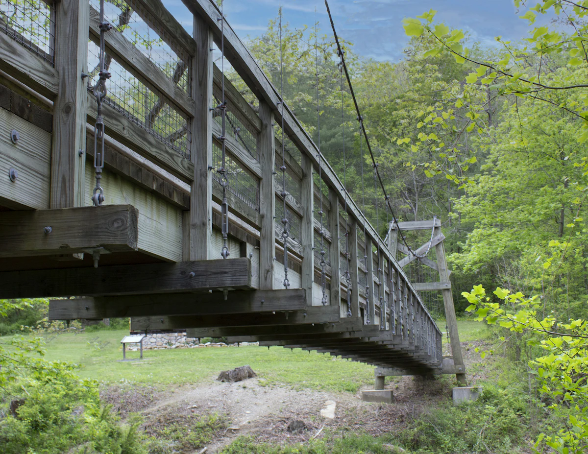 A wooden suspension footbridge over a stream among spring trees in Fort Valley, Virginia