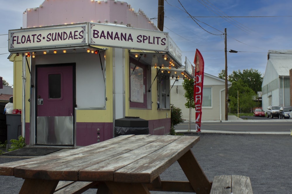 a wooden picnic table sitting in front of a banana shop