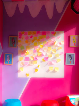 A vibrant workspace with colorful marketing strategy notes pinned on a soft cream wall, accented by fuchsia and charcoal stationery.