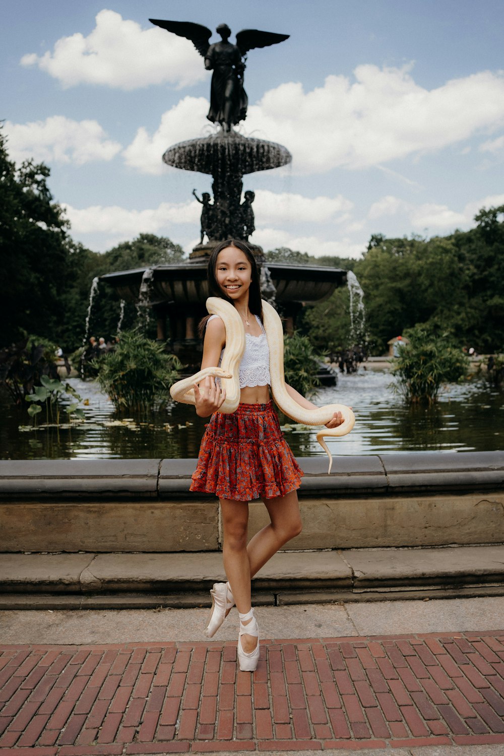 a woman in a red skirt holding a snake