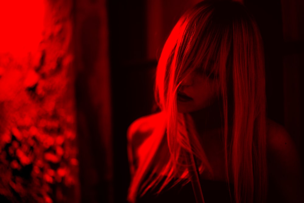 Una mujer parada en una habitación oscura con una luz roja