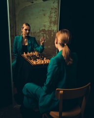 two women sitting at a table playing chess