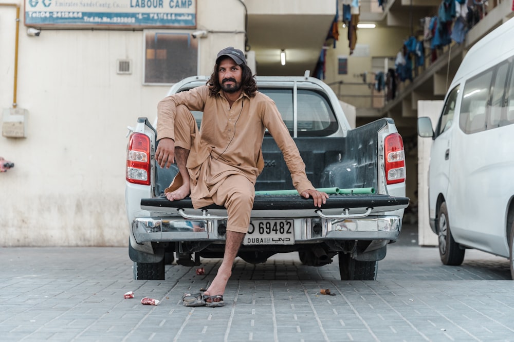 a man sitting on the back of a pick up truck