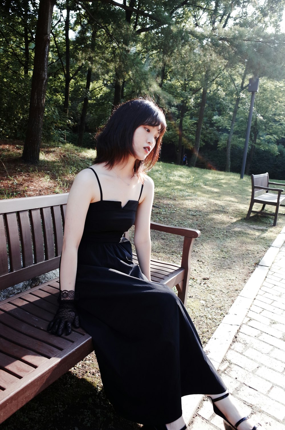 a woman in a black dress sitting on a bench