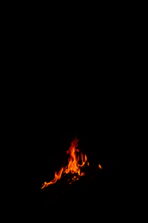 A minimalist black brasero with flickering flames, set against a dark background.