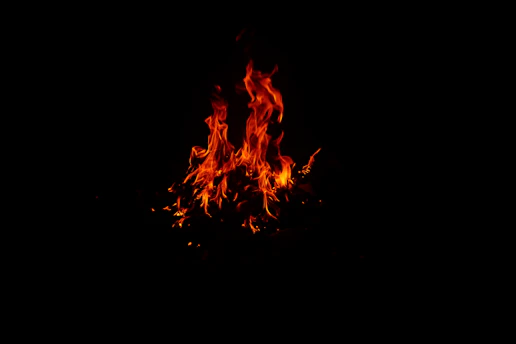 Close-up of a glowing orange flame against a dark industrial background, symbolizing energy and transformation.