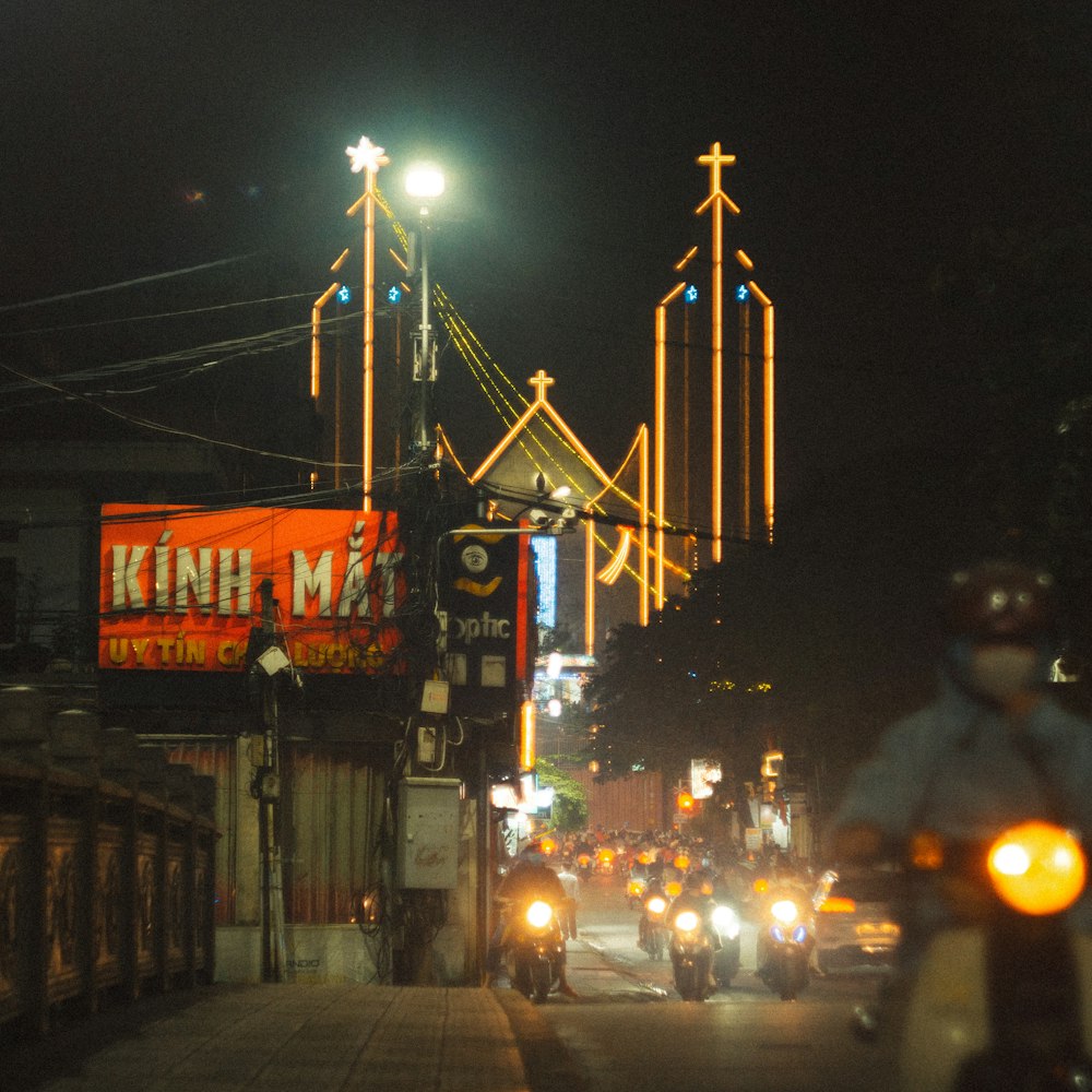 a group of people riding motorcycles down a street at night