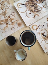 Close-up of hands organizing academic papers next to a cup of coffee.